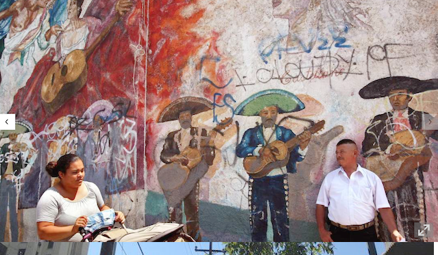 A mural of three men playing guitars and singing.